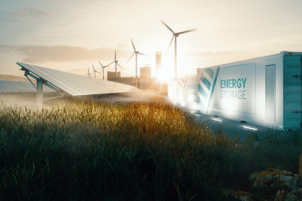 Solar panels installed in a grassy field with wind turbines in the background. To the right, there are large white containers labeled "Energy Storage." The sun is setting or rising behind a city skyline, casting a warm glow over the scene.
